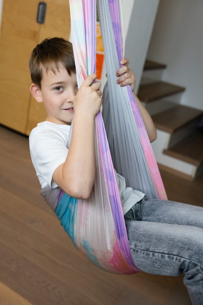 Kind schaukelt in einem Tuch während einer spielerischen Begleitung