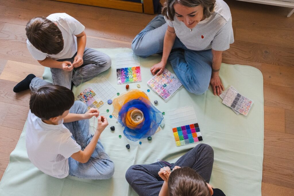 Kinder sitzen am Boden und arbeiten mit bunten Materialien