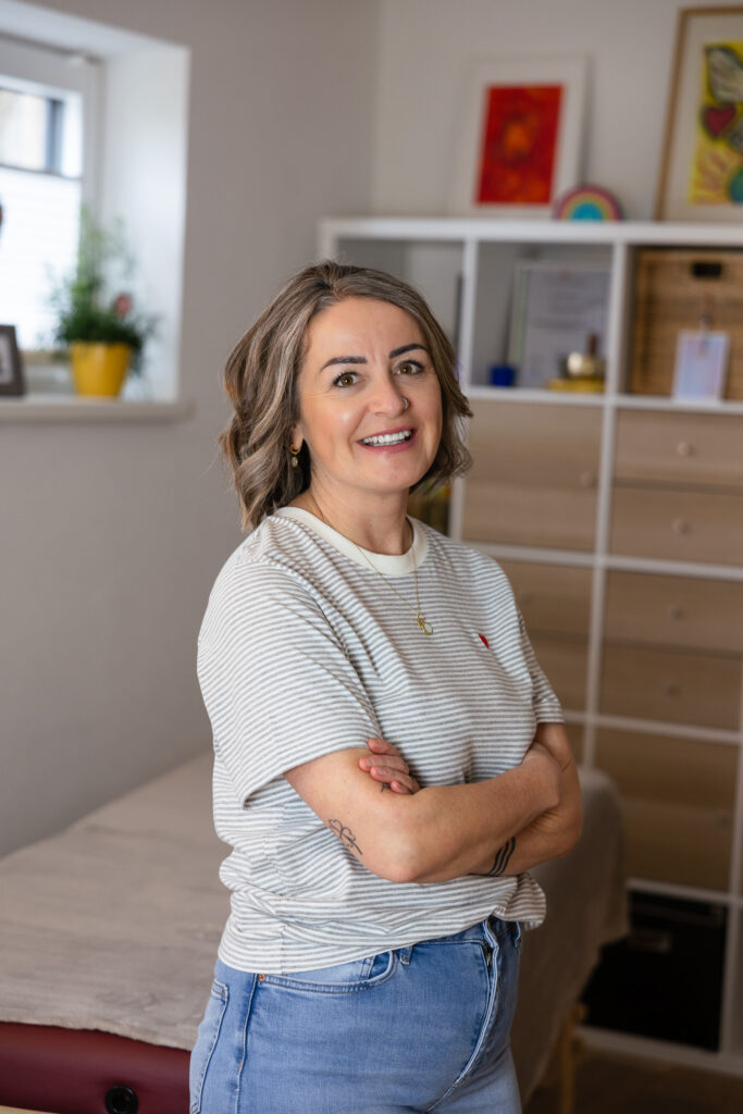 Kathrin Grufeneder mit verschränkten Armen in ihrer Praxis
