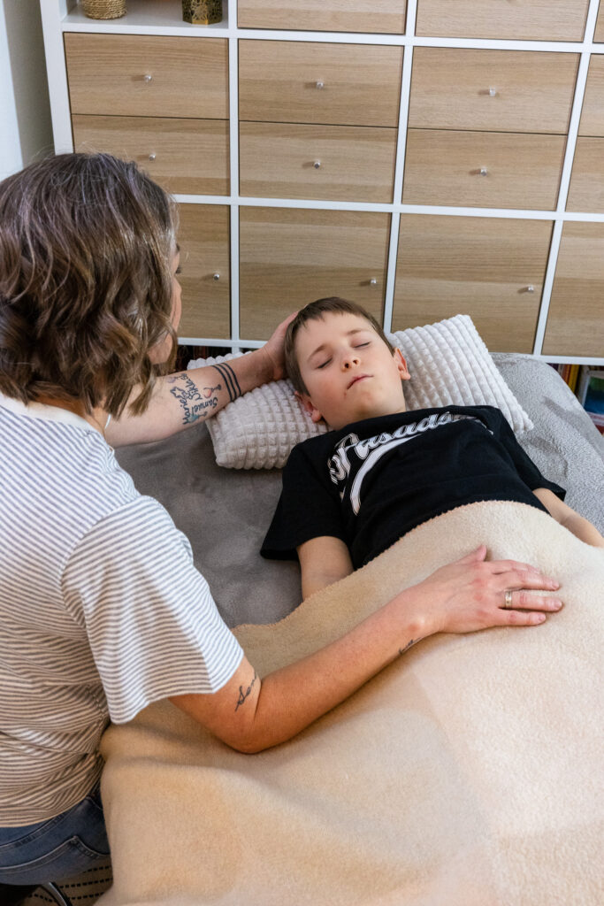 Kind liegt entspannt während einer craniosacralen Behandlung