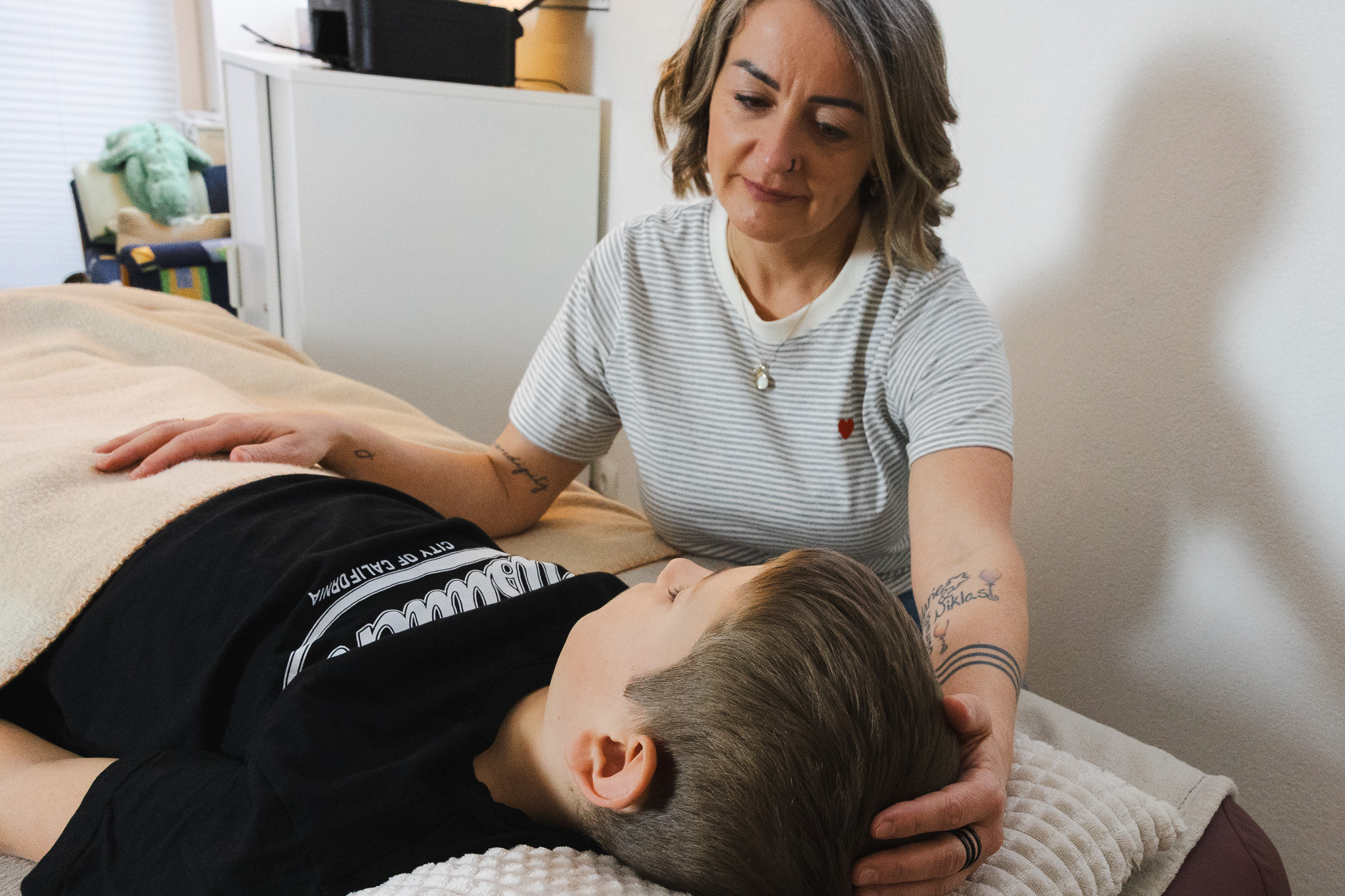 Frau gibt einem Kind eine craniosacrale Behandlung auf einer Behandlungsliege
